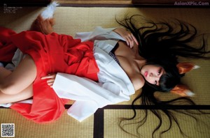 A woman in a red and white dress sitting on a wooden floor.