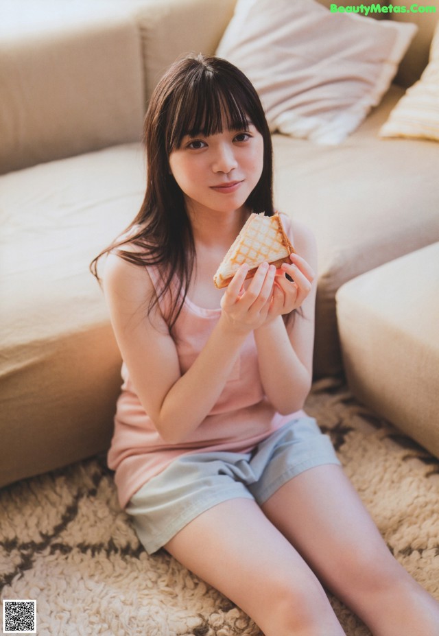 A woman sitting on the floor holding a piece of food.