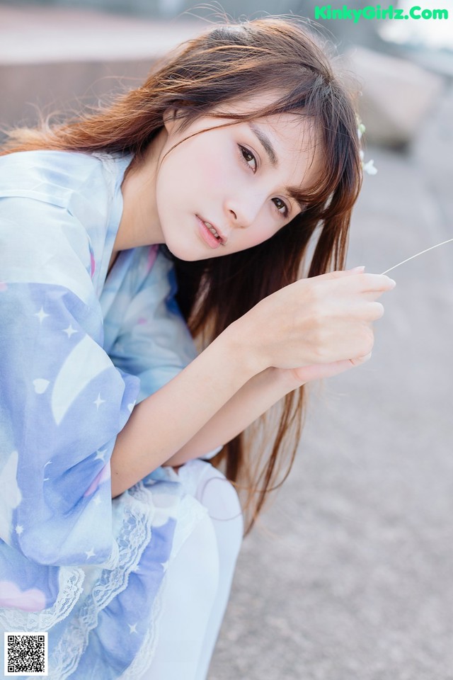 A woman in a blue kimono sitting on the ground.