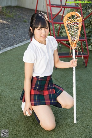 A woman in a school uniform holding a lacrosse stick.