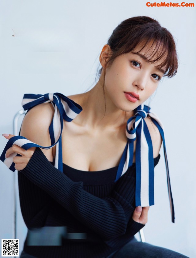 A woman in a black top and blue and white striped scarf.