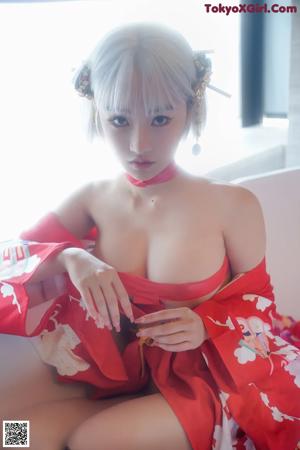 A woman in a red kimono sitting in a bathtub.