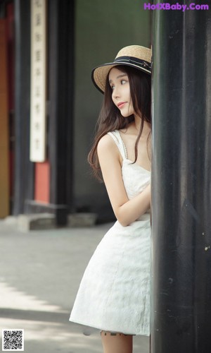 A woman in a white lingerie sitting on a chair.