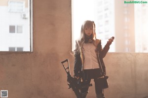 a woman sitting on the ground with a gun in her hand