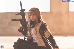 A woman in a black and yellow jacket holding a gun.