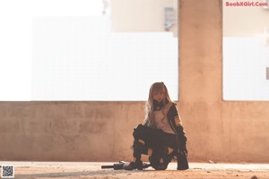 a woman sitting on the ground with a gun in her hand