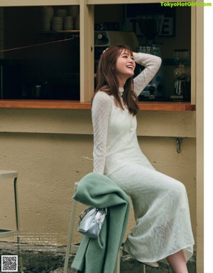 A woman in a green dress and a white coat is walking down the street.