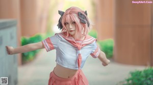 A woman in a pink and white outfit pointing at the camera.
