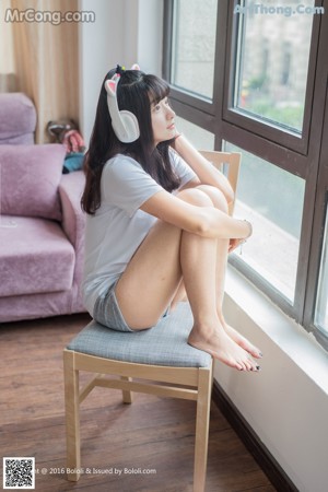 A woman in a white shirt and gray shorts holding a stuffed animal.