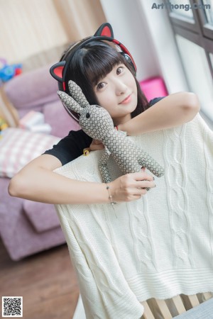 A woman sitting on the floor wearing a cat ears headband.