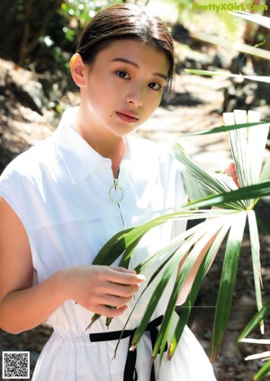 A woman leaning against a wall with her hands on her hips.