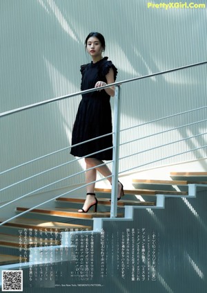 A woman leaning against a wall with her hands on her hips.