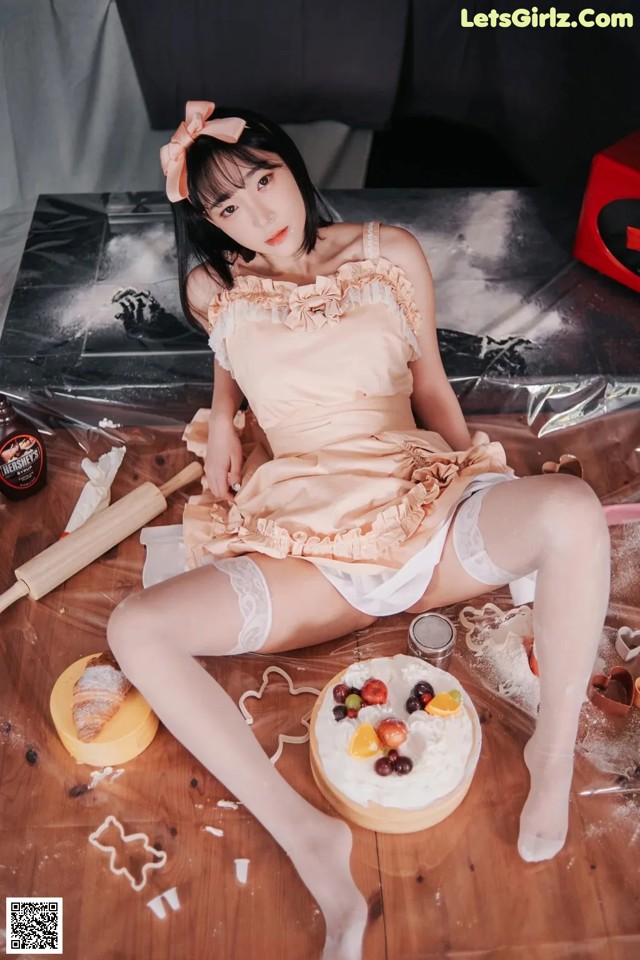 A woman sitting on the floor next to a cake.