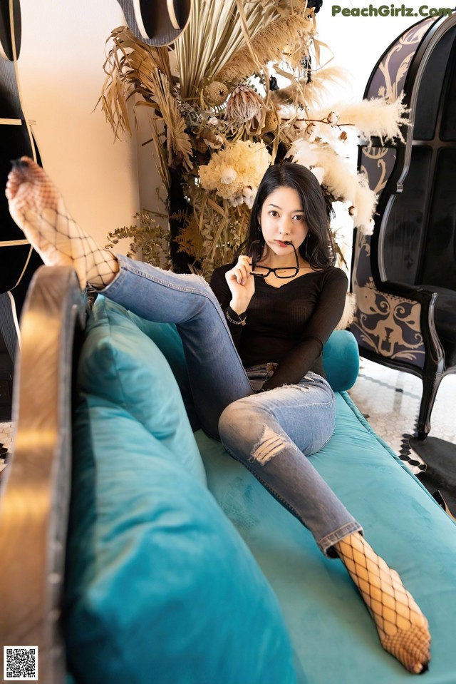 A woman sitting on a blue couch with her legs crossed.
