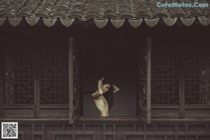 A naked woman standing in a bathroom next to a toilet.