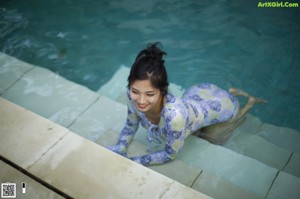 A woman in a white bathing suit standing next to a hot tub.