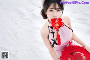 A woman in a red dress sitting in the snow.