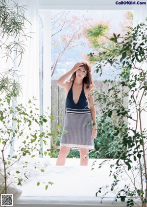 A woman in a blue and white striped shirt leaning against a wall.