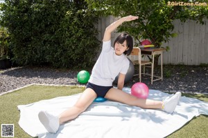 A woman in a white shirt and black shorts holding a pink ball.