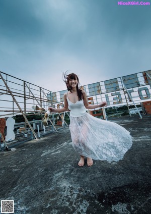 A woman in a white tank top leaning against a metal railing.