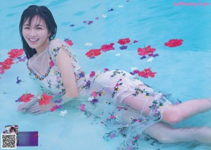 A woman sitting on a wooden dock next to a body of water.