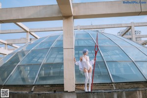 A woman in a white outfit is holding a red ribbon.