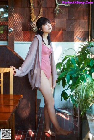 A woman in a pink dress standing on a porch.