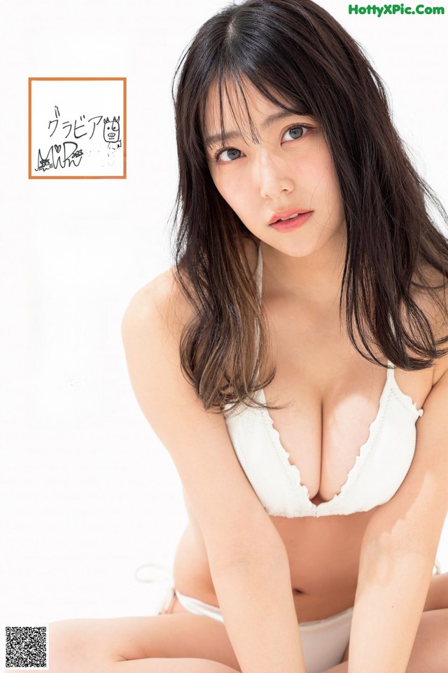 A woman in a white bra and panties sitting on the ground.