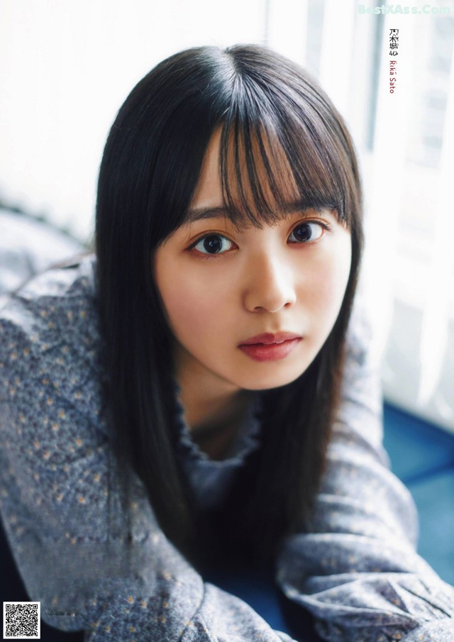 A woman with long black hair sitting on a couch.