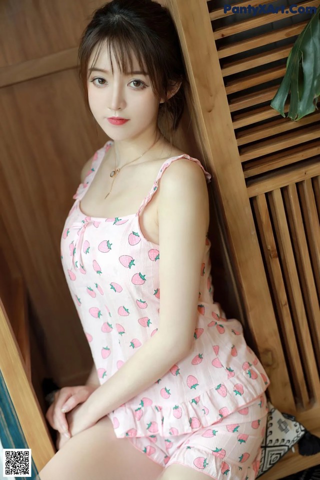 A woman in a pink dress sitting on a wooden bench.