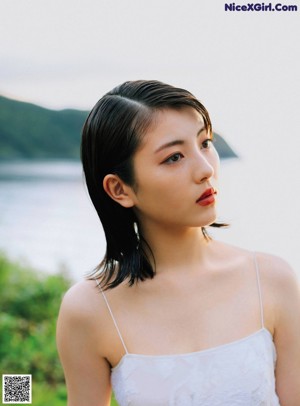 A woman in a white dress standing on a beach.