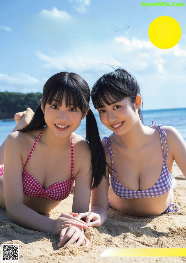 A couple of women laying on top of a sandy beach.