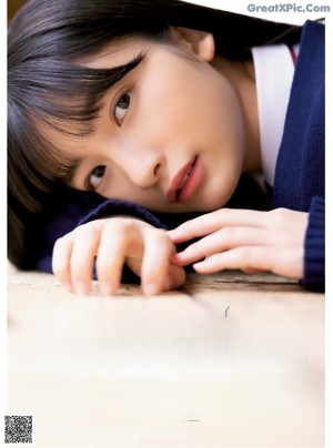 A young woman in a school uniform leaning against a tree.