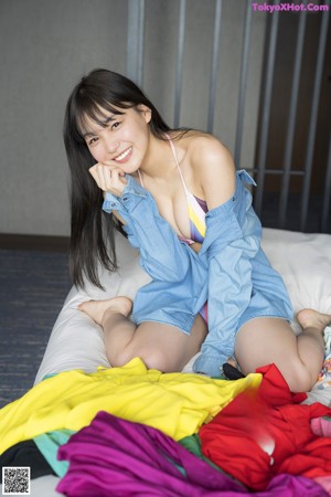 A woman in a bikini and a denim shirt posing for a picture.