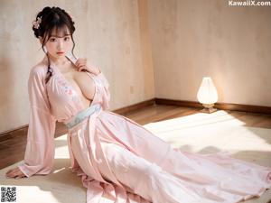 A woman in a yellow kimono sitting on a wooden bench.