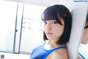 A woman in a blue swimsuit standing in a bathroom.