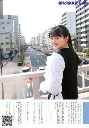 A woman standing on a balcony in a city.