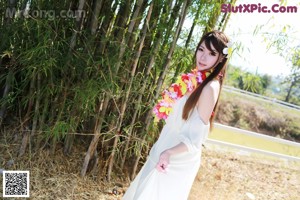 A woman in a white dress sitting under a tree.