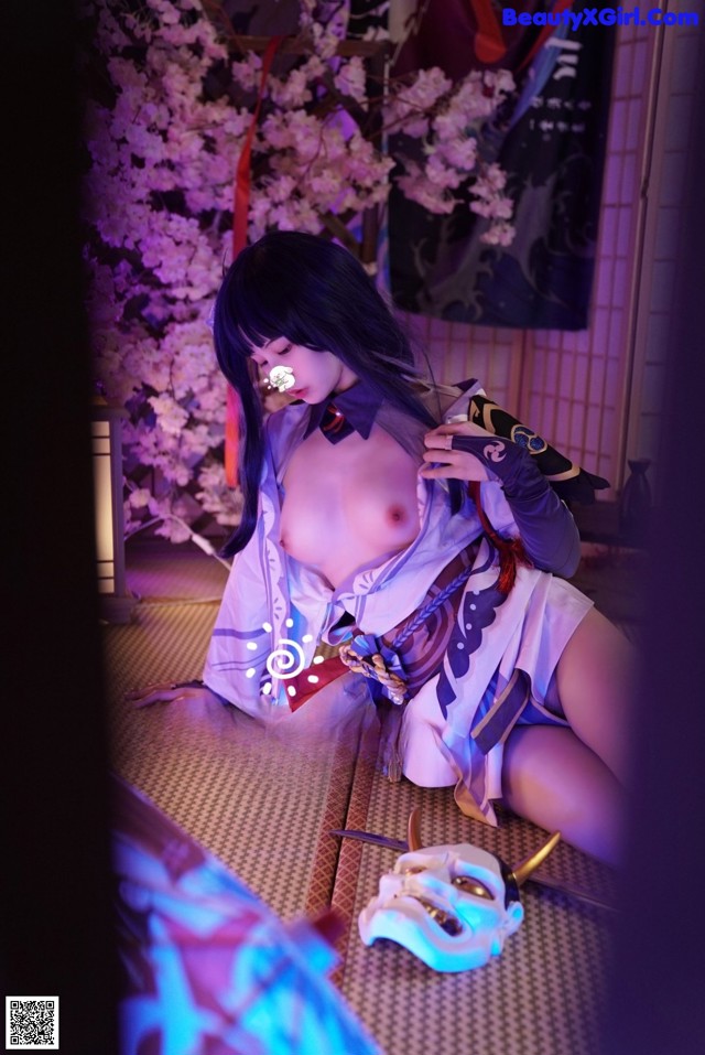 A woman in a kimono sitting on the floor next to a mask.