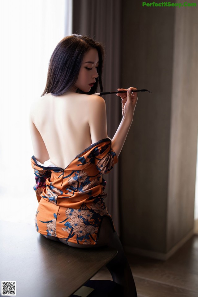 A woman in a kimono sitting on a table smoking a cigarette.