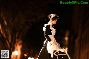 A woman in a maid outfit sitting on a chair.