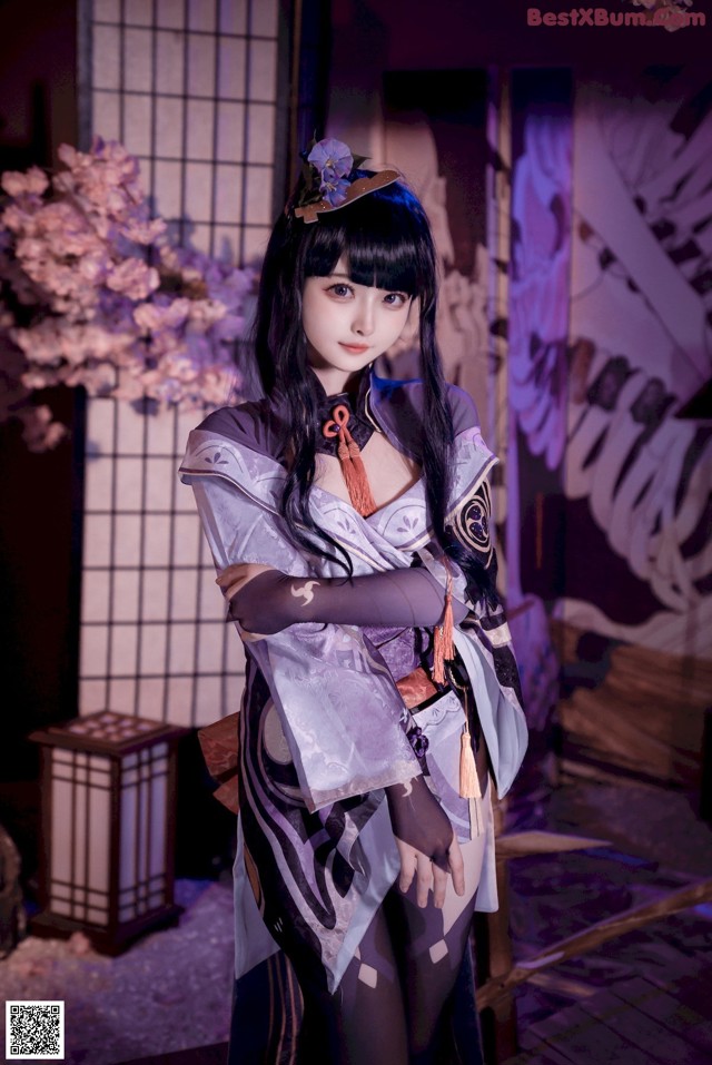 A woman in a kimono standing in front of a window.