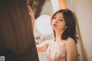 A woman in lingerie leaning against a wooden door.