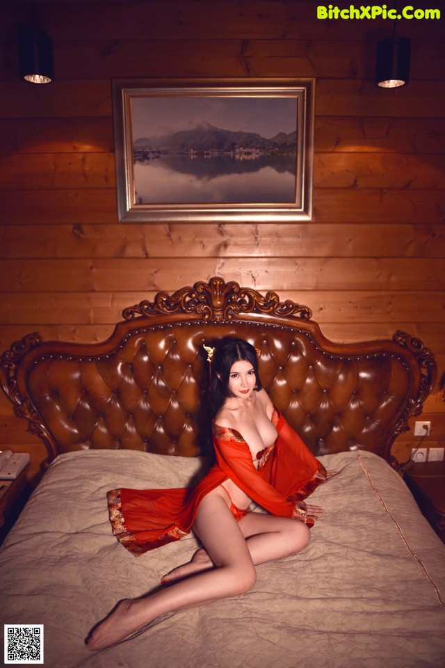 A woman in a red lingerie sitting on a bed.