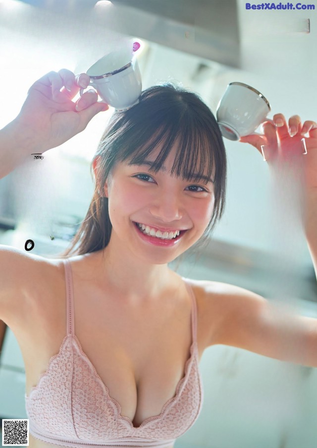 A woman in a pink bra holding a cup of coffee.