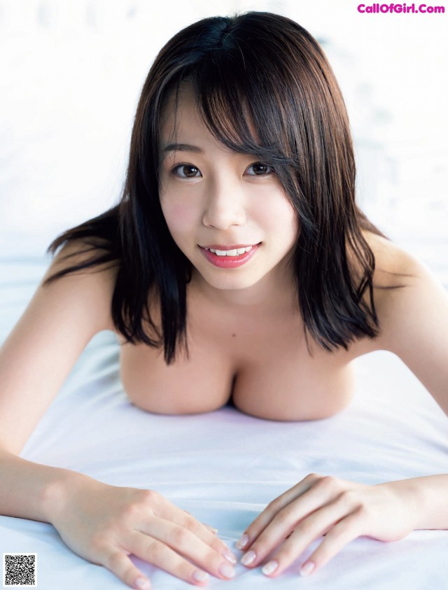 A woman laying on top of a bed with her hands on her breasts.