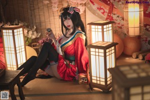 A woman in a red kimono sitting on the floor.