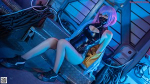 A woman in a latex outfit posing in front of a computer.