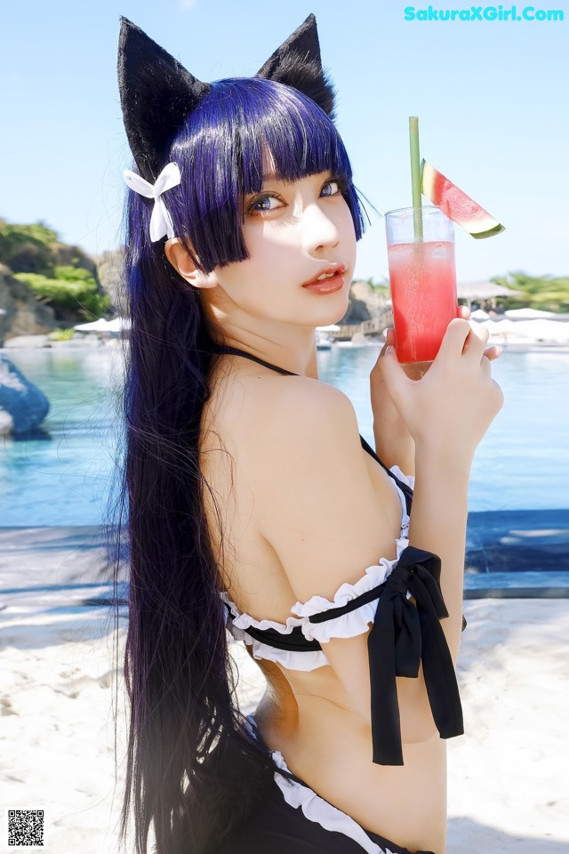 A woman in a bikini holding a drink on the beach.