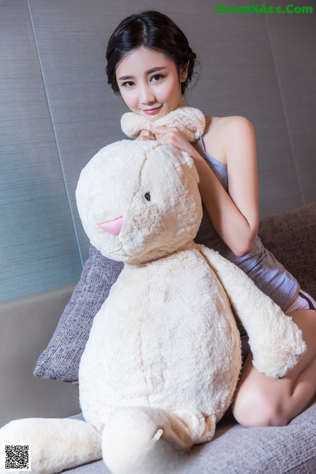 A woman sitting on a couch holding a large stuffed animal.